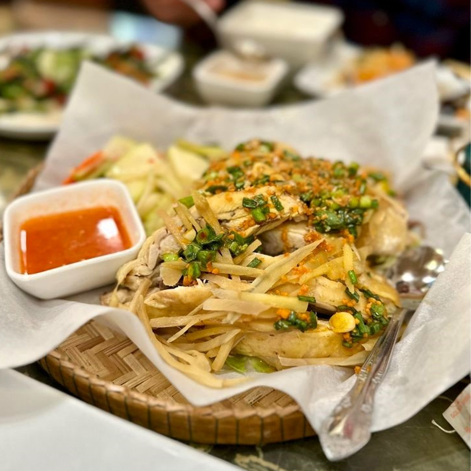 Cambodian chicken dish with ginger, green onions, and chili sauce, served in a woven basket.