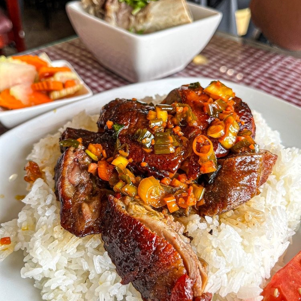 Cambodian roasted duck with sweet and sour sauce over white rice, with pickled vegetables.